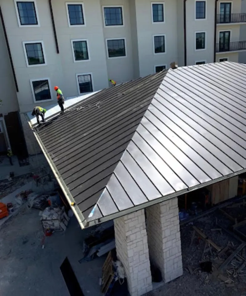 Crew installing standing seam metal roof panels on a commercial project in Eaton